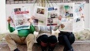 Auf einem Bürgersteig sitzen drei Personen, die Zeitungen lesen und deren Köpfe dahinter versteckt sind. Auf den Zeitungen sind die Titel zu lesen: "Latercera", "Condor" und "El Mercurio". (dpa/ Arne Dettmann)
