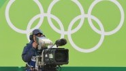 Ein Kameramann steht bei den Olympischen Spielen in Rio vor einer grünen Wand mit den Olympischen Ringen (picture alliance / dpa / Sebastian Kahnert)