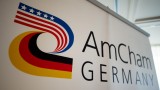 Auf einer Fotowand ist das Logo der Amerikanischen Handelskammer in Deutschland, der AmCham Germany, im Hotel "Hilton Park" in München (Bayern) zu sehen.  (picture alliance / dpa / Inga Kjer)
