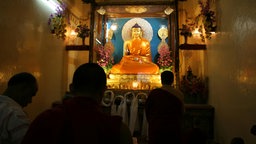 Im Gebetsraum lächelt eine vergoldete Buddha-Statue auf Gläubige herab